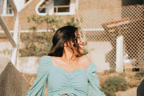 Woman In Blue Smiles And Leans Back Outdoors Photo