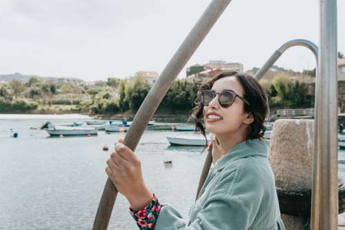 Woman In Sunglasses Smile For The Camera With Boats Below Photo