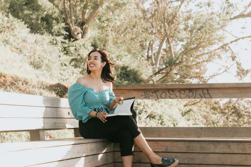 Woman Reads A Book On A Bench Outdoors Photo