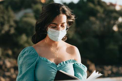 Close Up Of Woman Reading In A Blue Face Mask Photo