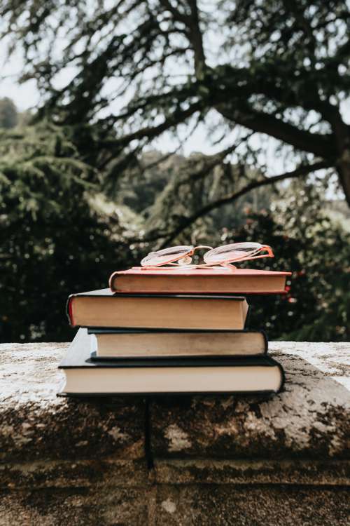 A Stack Of Hardcover Books Outdoors With Glasses Photo