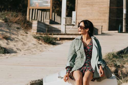 Woman In Floral Dress Sits By A Wooden Boardwalk Photo