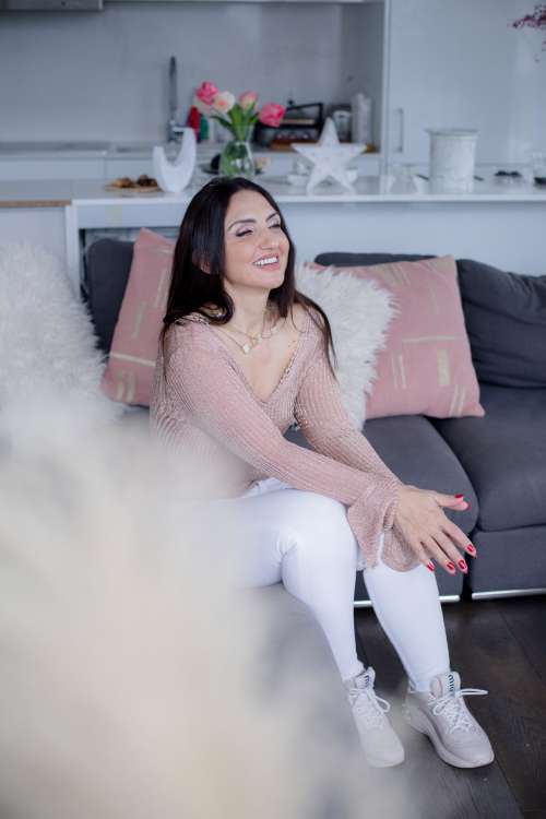 Woman Sits On A Grey Couch Smiling With Eyes Closed Photo