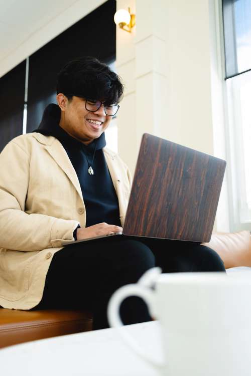 Man Smiles And Looks At Laptop Screen Photo