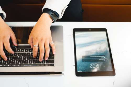 Hands Type On A Laptop That Is Next To A Tablet Photo