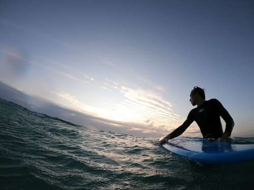 Person Standing In Wavy Water Holding A Surfboard Photo