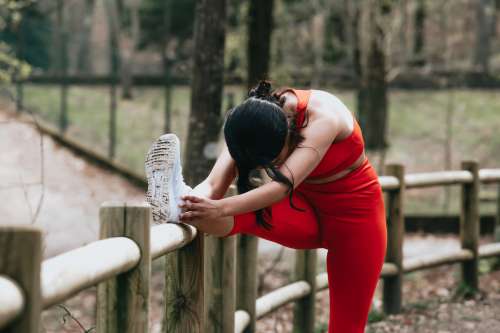 A Woman Stretches Outdoors Against A Wooden Fence Photo