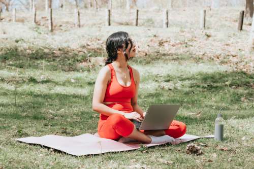 Sitting On Yoga Mat While Working On A Laptop Outdoors Photo