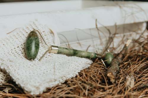 Jade Face Roller Lays On White Cloth With Pine Needles Photo