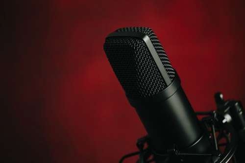 A Black Mounted Metal Microphone Against Red Photo