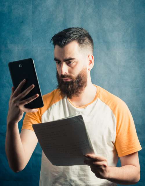 Man Holds A Phone And A Stack Of White Paper Photo