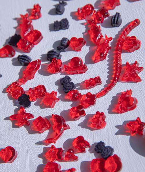 Red And Black Gummies On White Surface Photo
