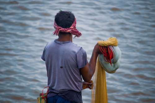 Person Holding A Fishing Net Faces Blue Water Photo