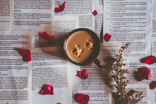 Camera Looks Down At A Mug With Petals Scattered Around It Photo