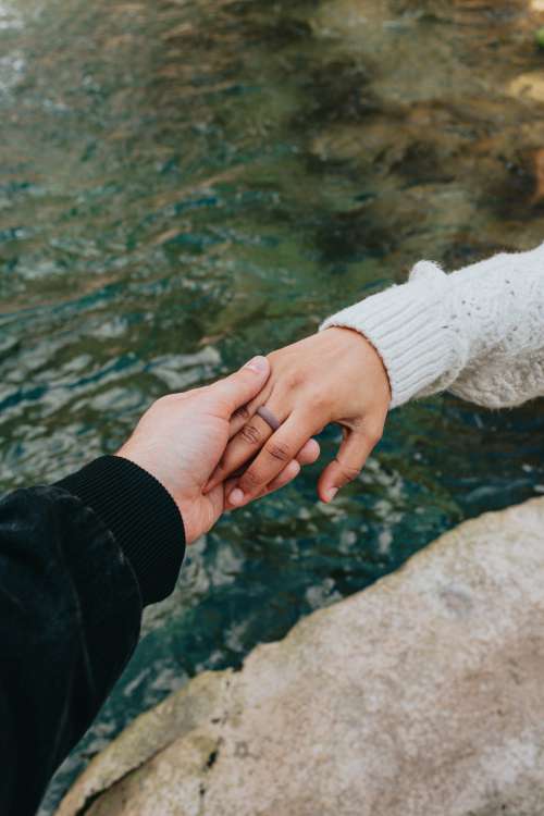 Hands Holding Each Other Above Blue Clear Water Photo