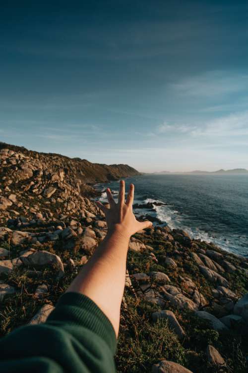 Landscape Of A Rocky Shore With A Hand Reaching Out To It Photo