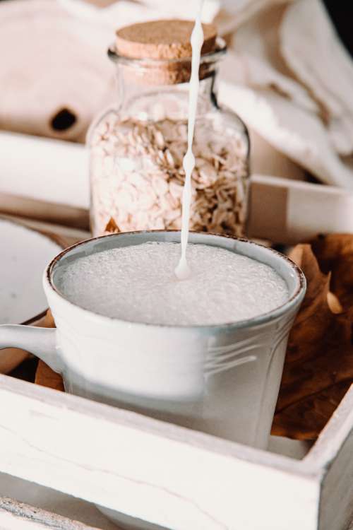 Frothy Milk Pouring Into A Ceramic Mug On Wooden Tray Photo