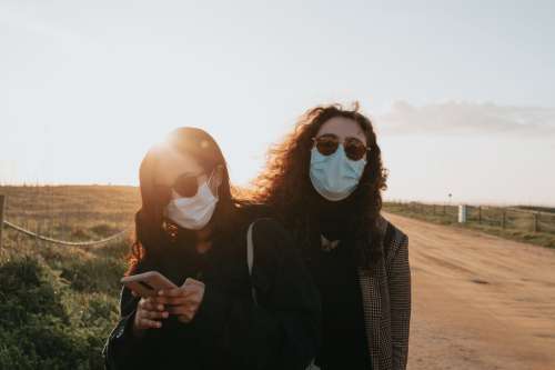Two Woman In Facemasks And Sunglasses Outdoors Photo