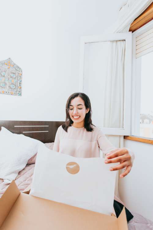 Woman Smiles And Opens A Box With White Tissue Paper Photo