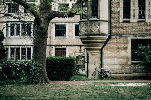 Bicycle Rests Against An Old Building With Green Grass Photo