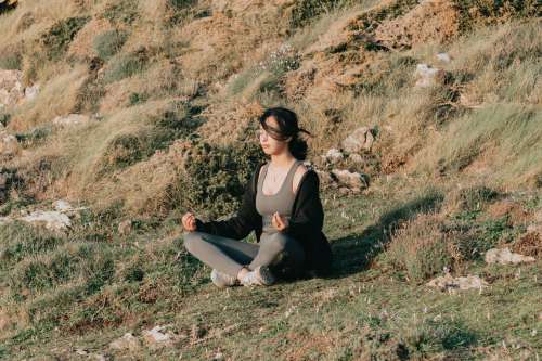 Woman Meditates Outdoors On A Green Grassy Hill Photo