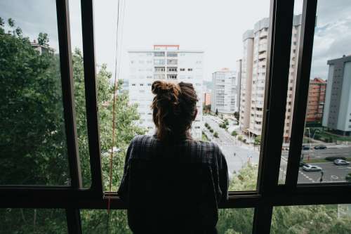 Person Looks Out An Open Window Toward City Below Photo