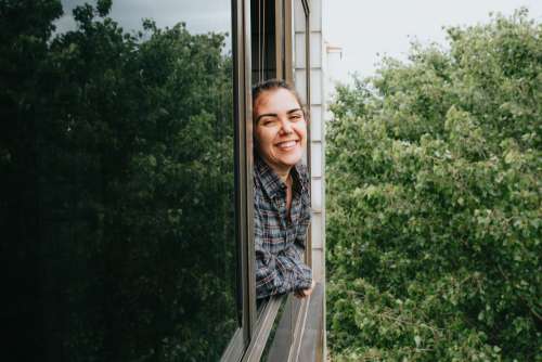 Woman With A Wide Smile Leaning Out A Window Photo