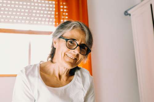 Woman Smiling To The Camera With Orange Curtains Behind Photo