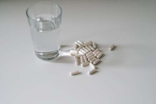 Glass Of Water And Pills On A White Countertop Photo