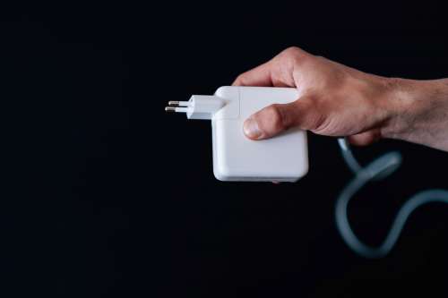 Hand Holds A Square Charger Against A Black Background Photo