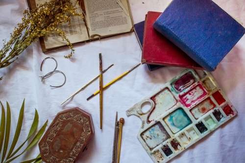 Flatlay Of Painting Supplies And Books With Dried Flowers Photo