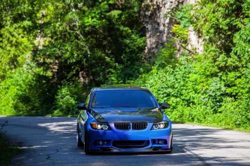 Blue Sports Car Drives Along Country Road Photo