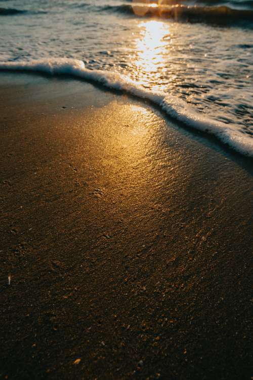 Golden Light On A Sandy Beach With Lapping Waves Photo