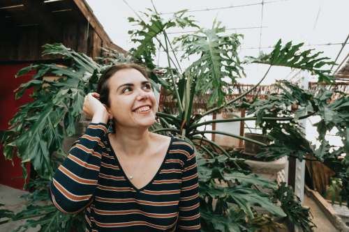 Woman Looks Up And Smiles By A Large Green Plant Photo