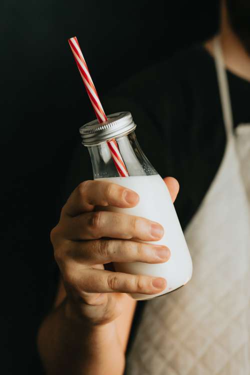 Hand Holds Clear Bottle Of Milk With A Straw Photo