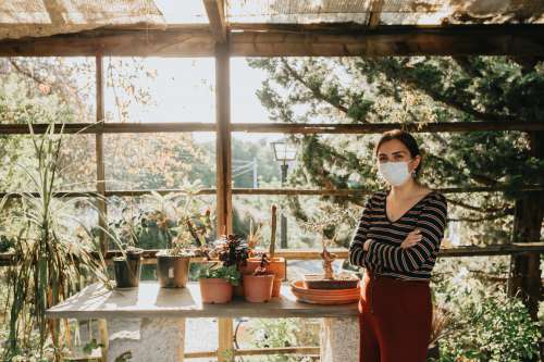 Woman In Facemask Next To Potted Plants On Table Photo