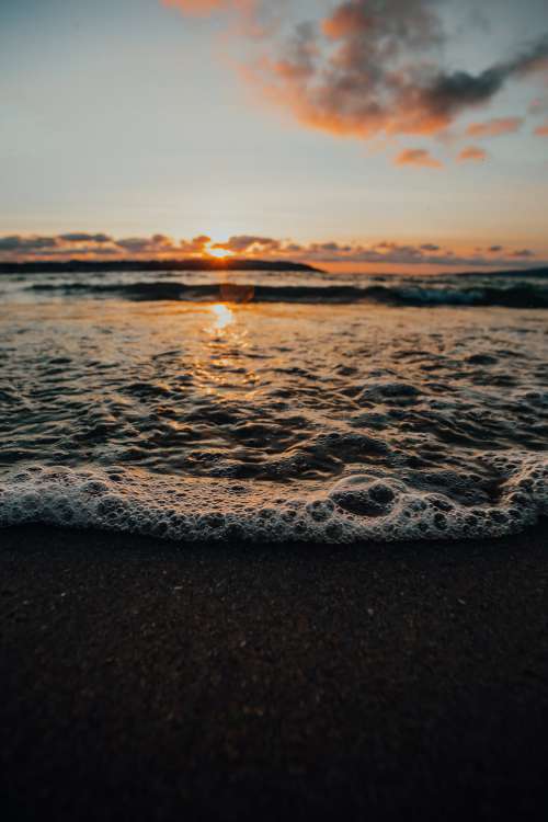 Close Up Of Waves And Bubbles On The Shore At Sunset Photo