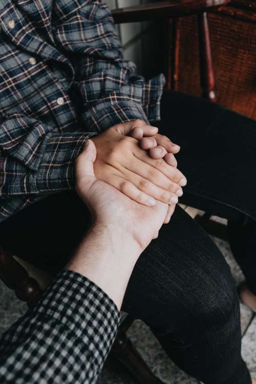 Two People Holding Hands While Sitting Down Photo