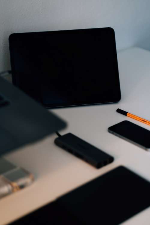 Desk With Some Black Gadgets In Focus Photo