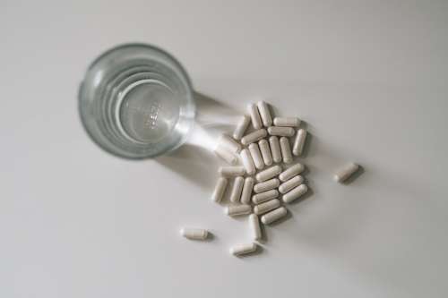 Top View Of A Glass Of Water And Pills On White Table Photo