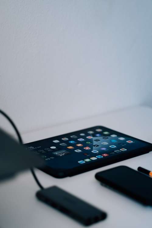 Tablet Lays On A White Table With Screen Lit By App Icons Photo