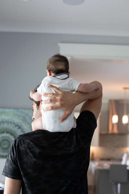 Adult Faces The Wall And Holds A Baby On Shoulders Photo