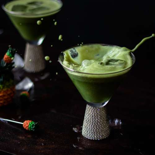 Foamy Green Drink Splashes In Cocktail Glass Photo