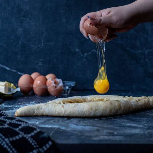 Cracking An Egg Above Fresh Dough On Marble Surface Photo