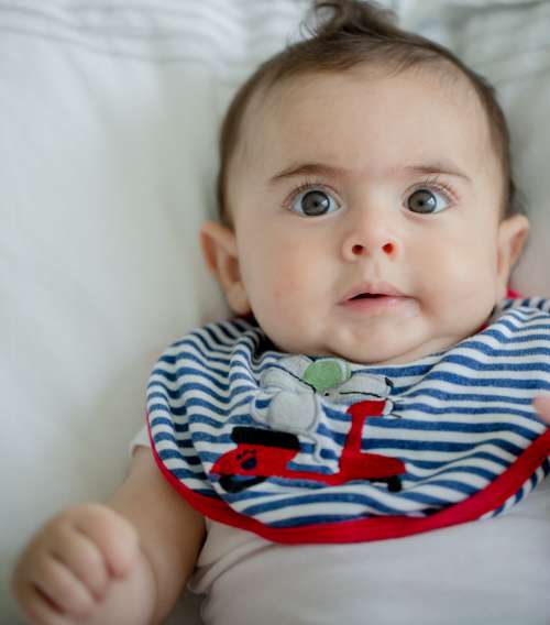 Photo Of A Small Child With Wide Eyes Wearing Bib Photo