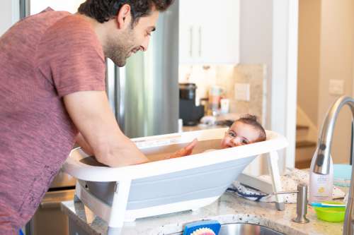 Person Bathes A Child In A Bathtub On Kitchen Counter Photo