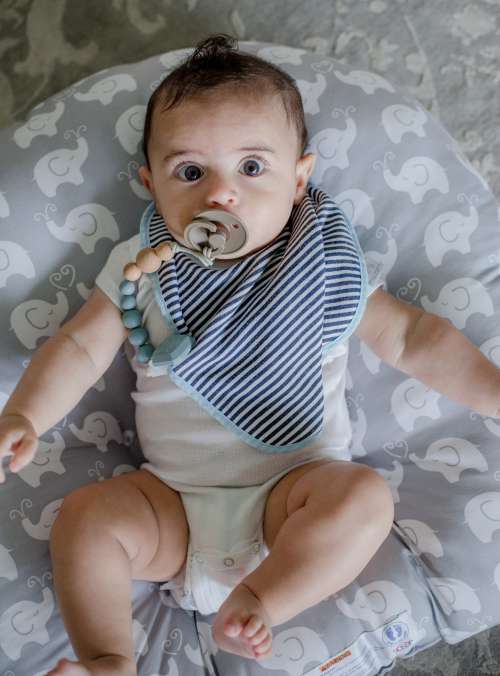 Camera Looks Down At A Baby With Wide Eyes And Pacifier Photo
