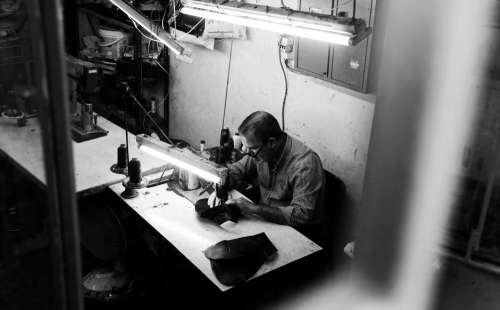 Black And White Photo Of A Person Sitting By Sewing Machine Photo