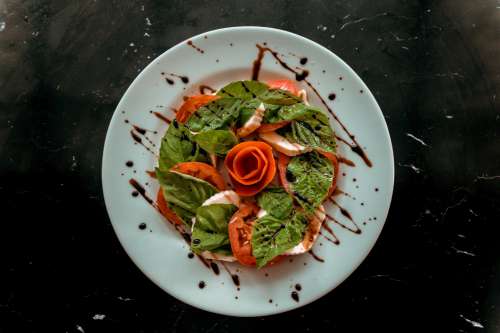 White Plate With A Caprese Salad On It And Dressing Photo