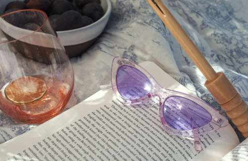 Purple Retro Sunglasses Lay On A Open Novel In The Sunshine Photo